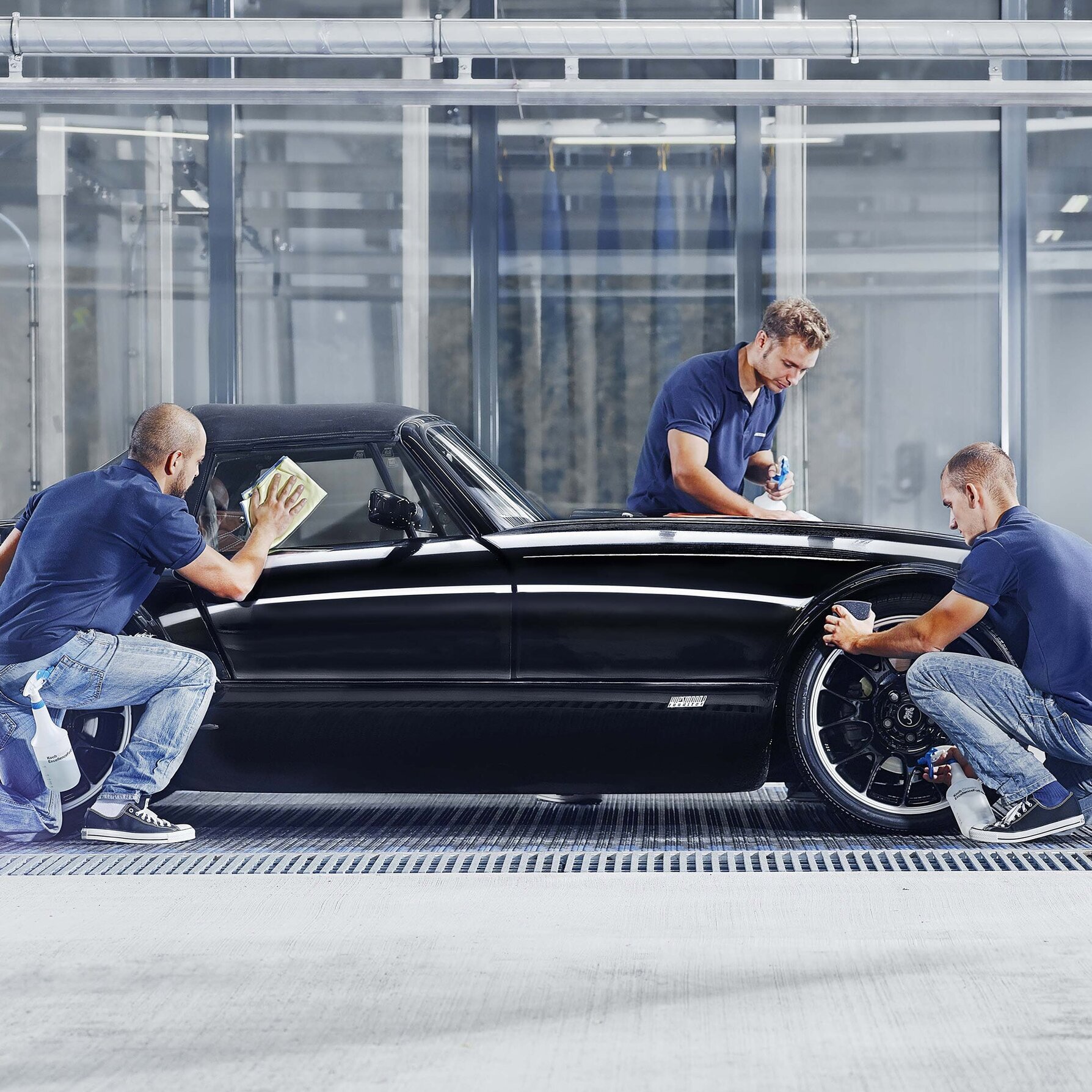 Employees clean a luxury car by hand in the car wash