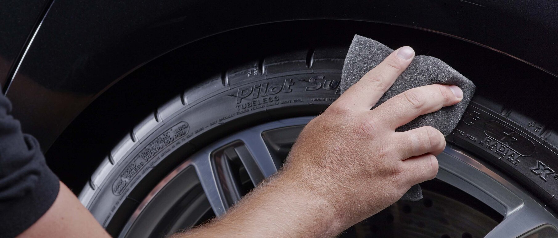 Man cleaning the tires of a black car